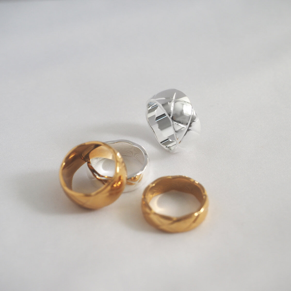 Beautifully crafted rings with distinctive "X" designs on a white background, emphasizing their polished gold and silver allure.