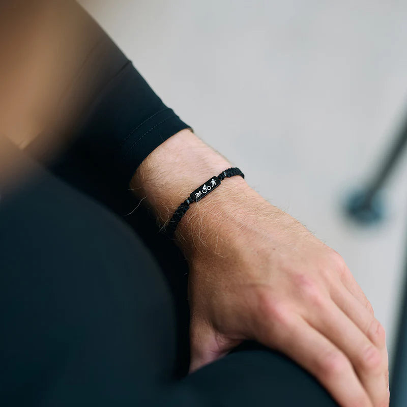 Person wearing a black bracelet on a neutral background