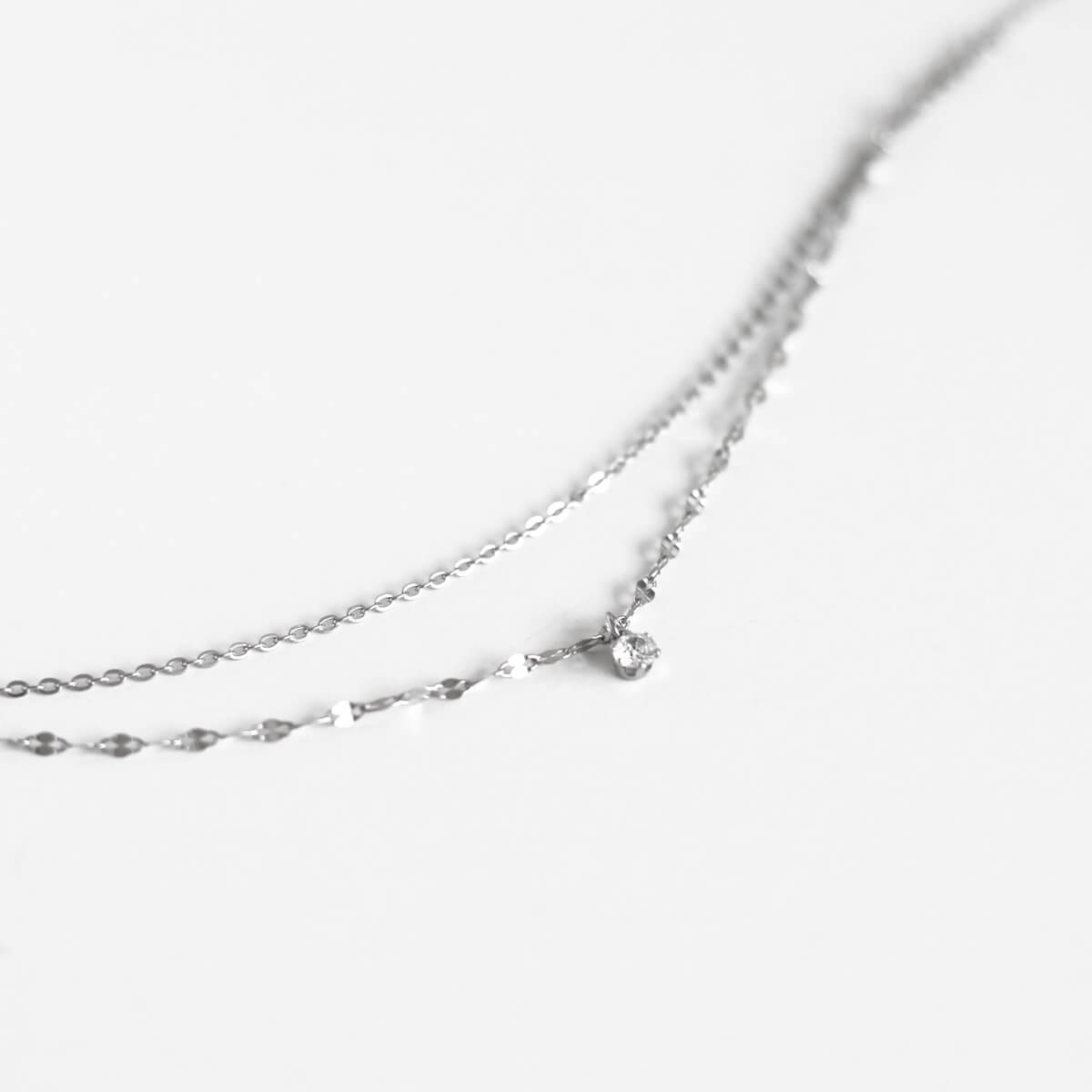 A close-up view of an elegant necklace featuring a sparkling crystal pendant, showcasing its intricate design and brilliance.