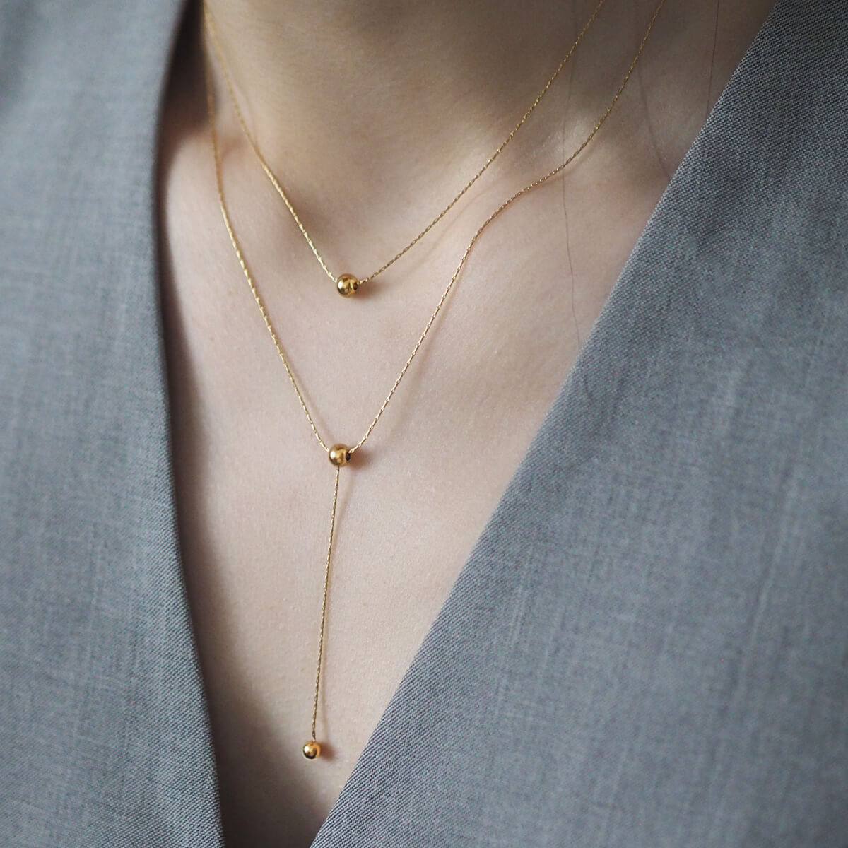 Stylish gold necklace with two small ball accents on a double-layer chain, ideal for adding a touch of elegance to your ensemble.