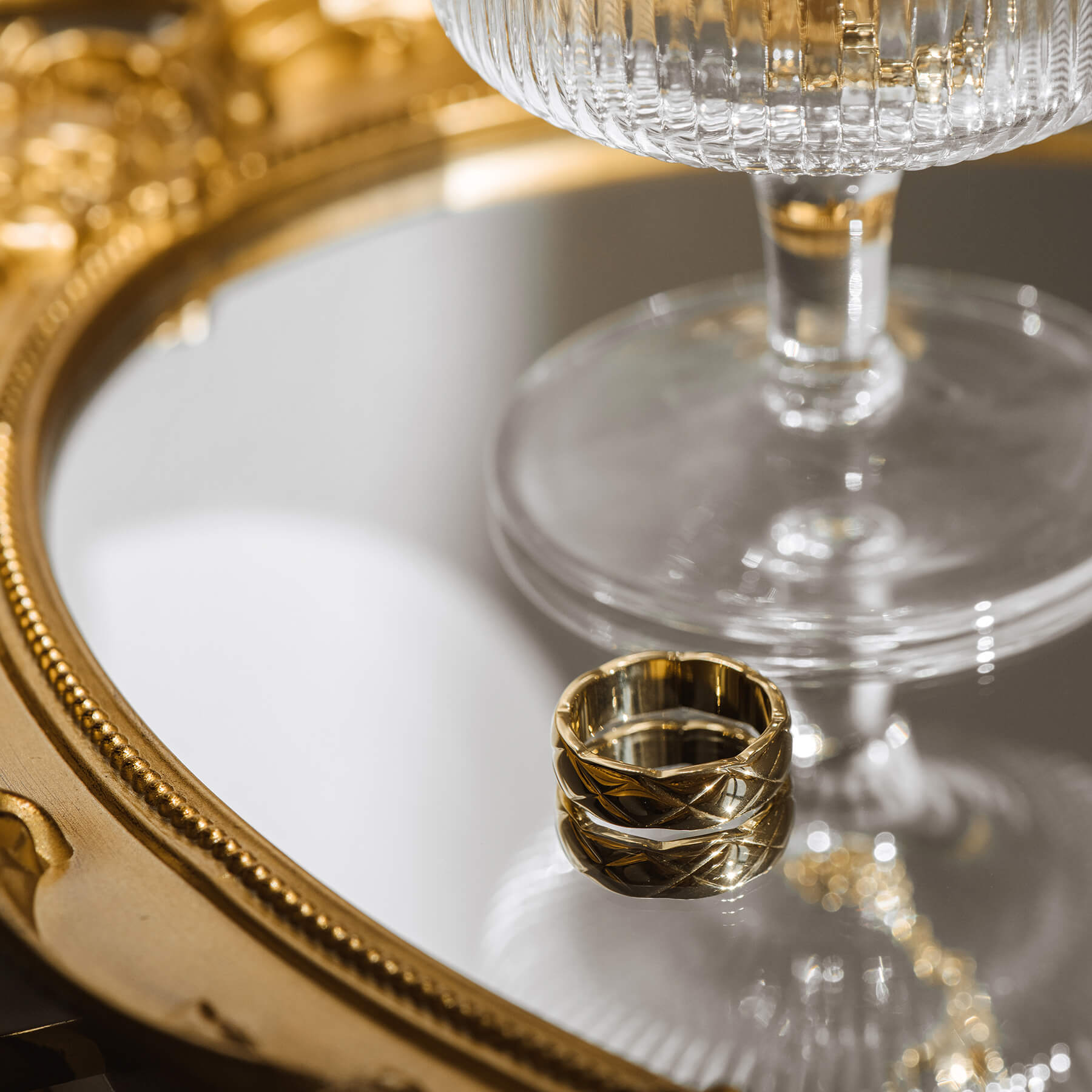 Elegant gold rings with unique "X" engravings, artfully arranged on a sleek mirror for a striking visual effect.
