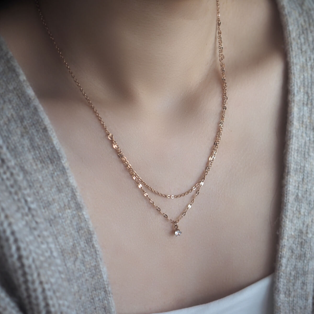 Elegant rose gold layered necklace adorned with a small crystal, perfect for adding a touch of luxury to any outfit.