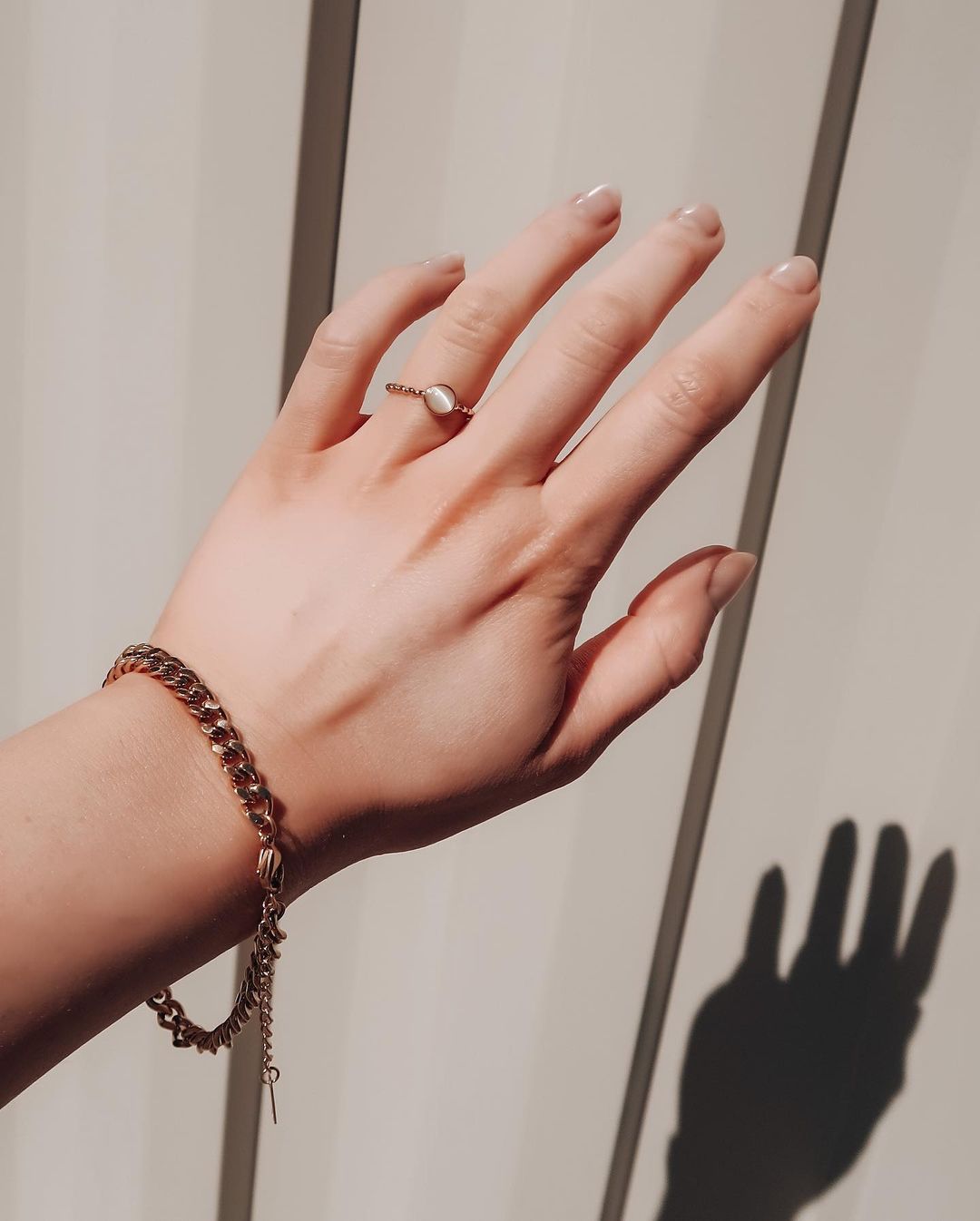 Close-up of a hand wearing a gold chain and an adjustable opal ring, highlighting classic beauty and everyday style.