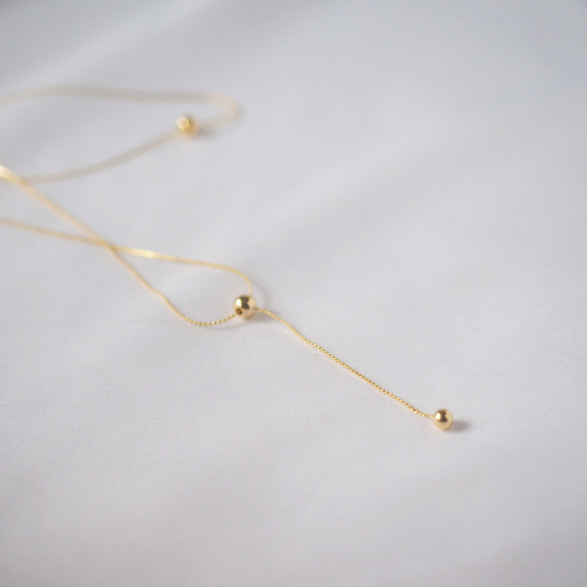 Stunning gold necklace featuring a long chain and a delicate ball pendant, ideal for adding a chic flair to your look.