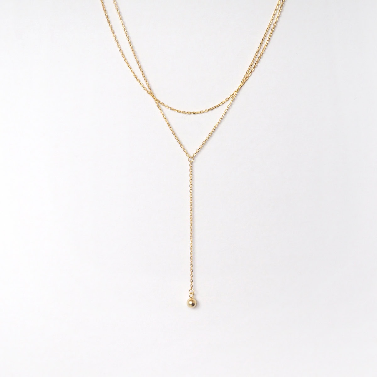 Close-up view of the Mone Ball Drop Necklace showing dual gold vermeil chains and a dangling bead.