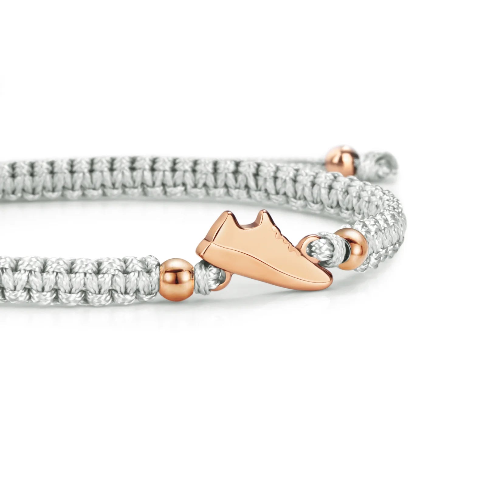 Close-up of the Rose Runner Grey Braided Bracelet featuring a rose gold sneaker charm and metallic beads on a grey woven band.