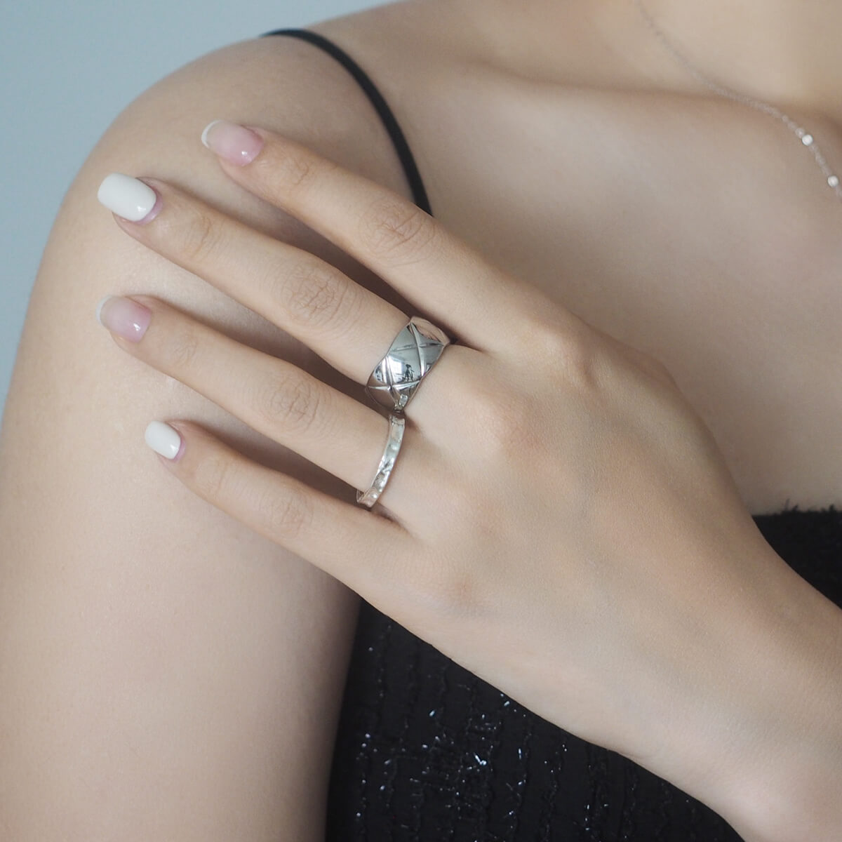 Close-up of a woman's hand adorned with a striking silver ring featuring deep "X" engravings, blending elegance and style.