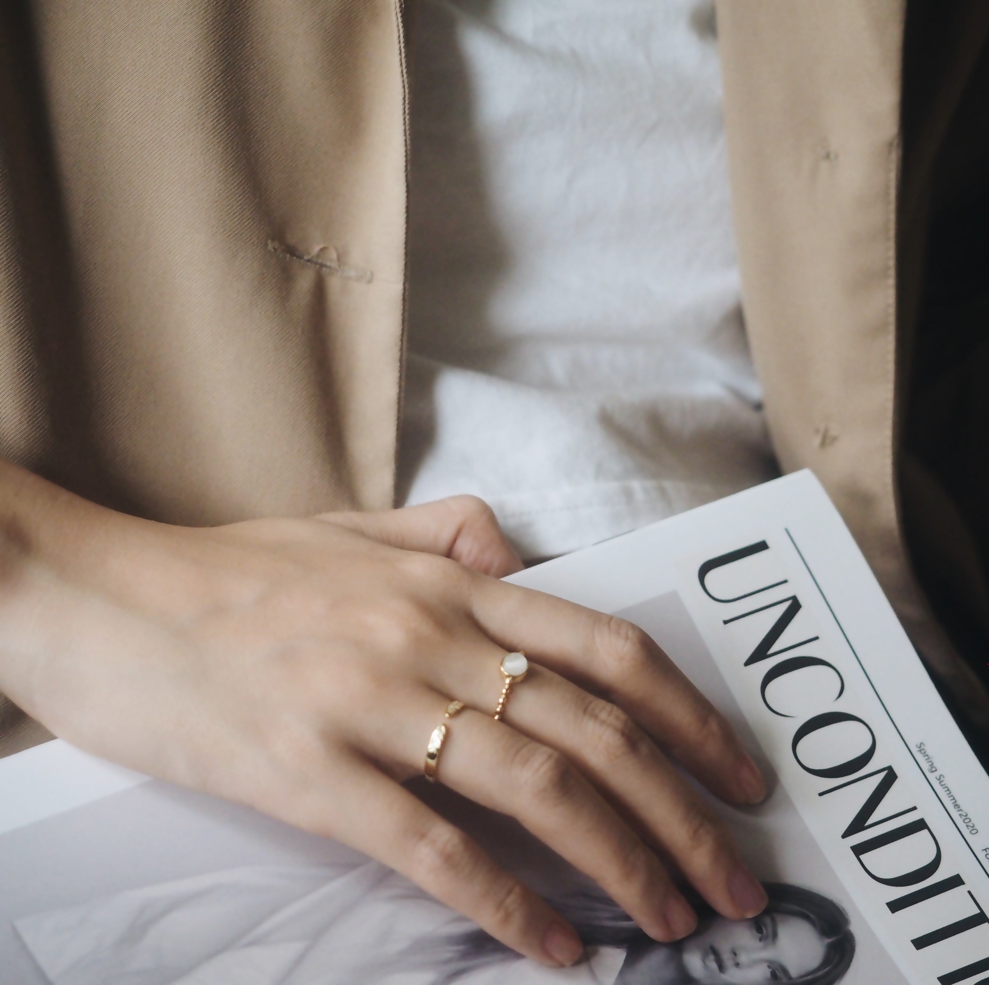 A hand with a beautiful opal ring holds a magazine, emphasizing the ring's classic design and adjustable fit.