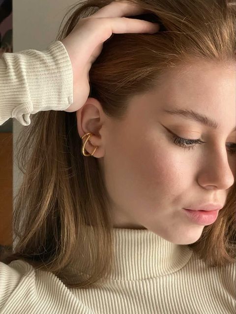 A woman in a turtleneck sweater, showcasing elegant Hillary Layers Earrings with a chic helix spiral design.