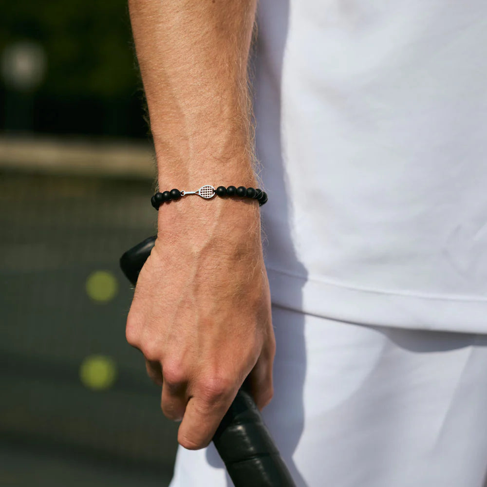 Person wearing a black beaded bracelet on a blurred background