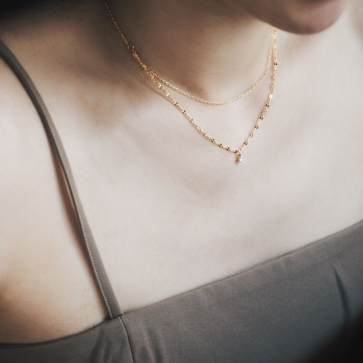 A woman elegantly wearing a gold necklace and a gold chain, highlighting her sophisticated fashion choice.