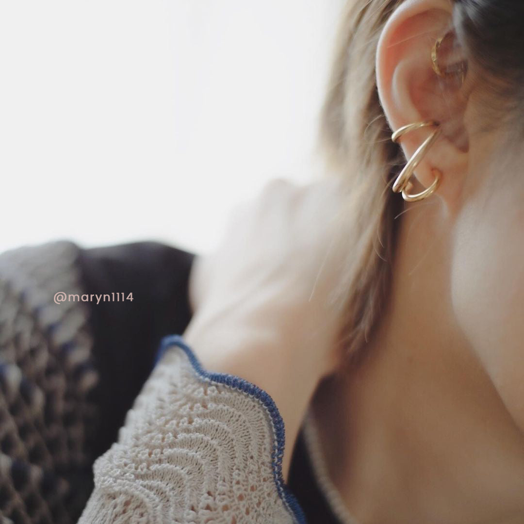 A woman models exquisite gold-plated earrings, the Hillary Layers, featuring a timeless helix spiral design for added flair.