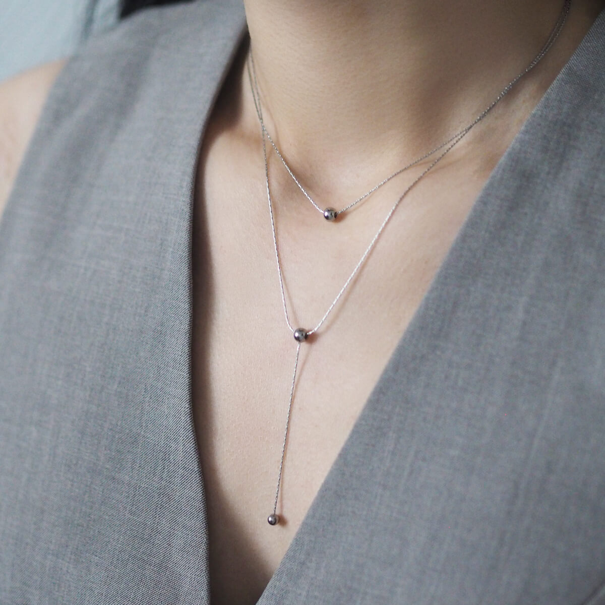 A woman models a minimalist double chain necklace with two small stones, enhancing her style with a touch of elegance.