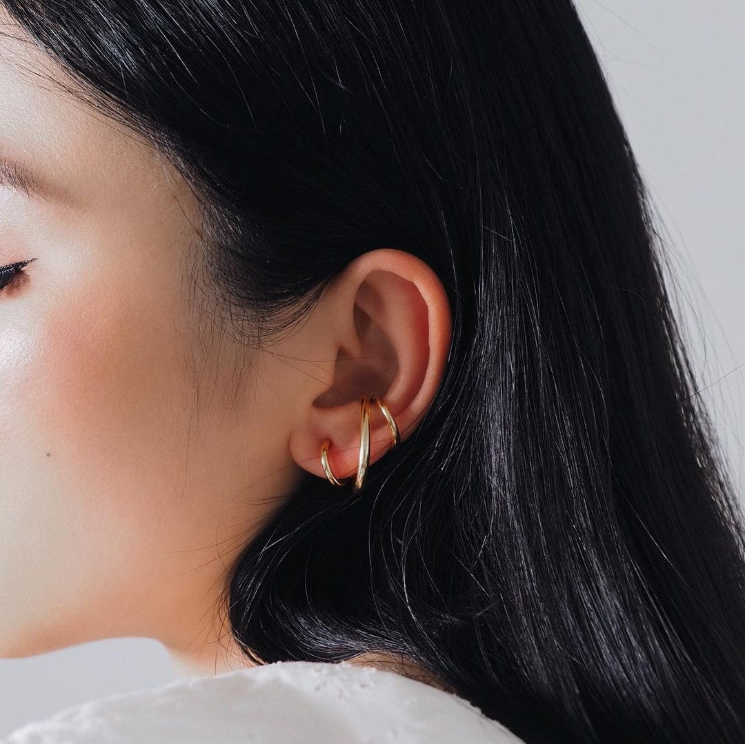 A woman showcases a stunning gold ear cuff, featuring a timeless helix spiral design in 18K gold plating.