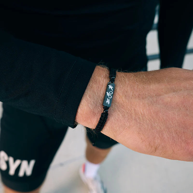 Person wearing a black bracelet on a blurred background