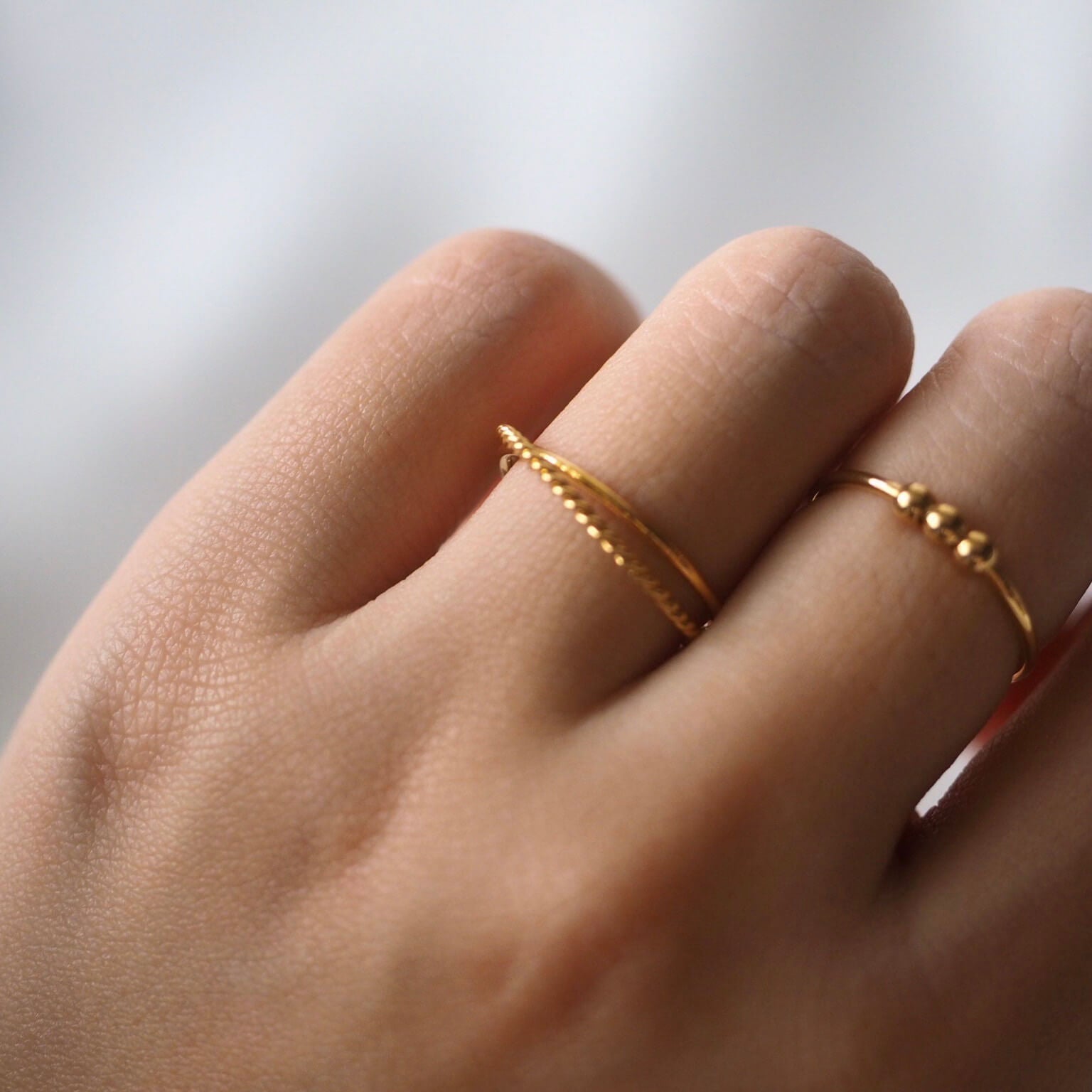 A woman's hand displays two stunning gold rings, capturing their elegance and the warmth of the gold against her skin.