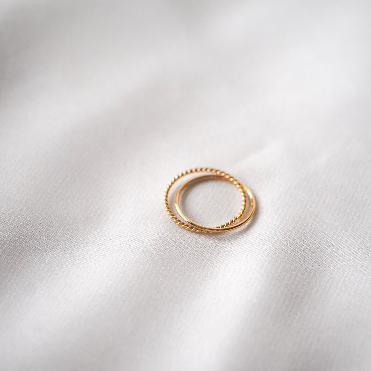 A stunning gold ring atop a clean white sheet, emphasizing its radiant glow and delicate details against the soft background.