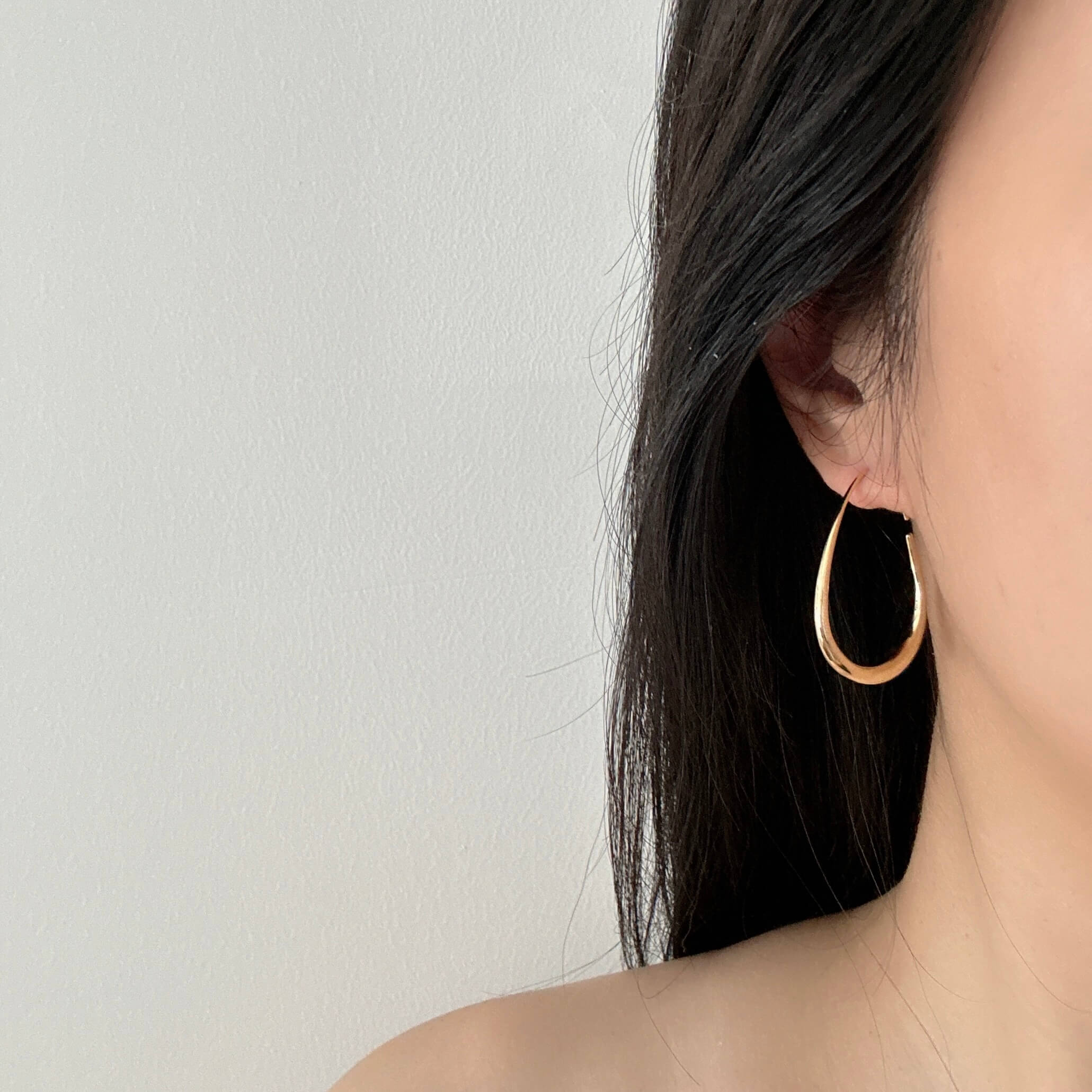 Close-up of a woman with a gold hoop earring on her right ear, highlighting her chic accessory choice.