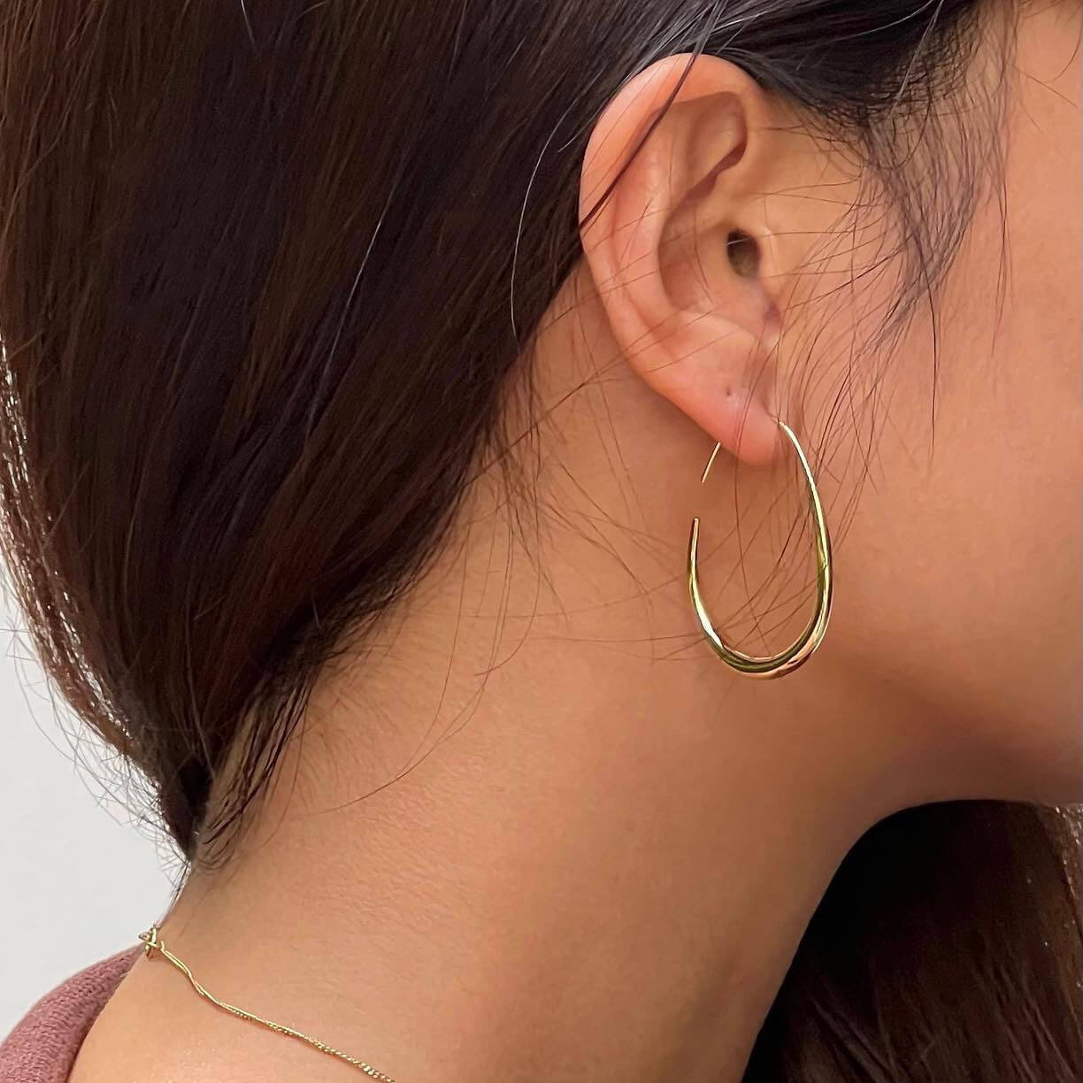 A woman showcasing elegant gold hoop earrings, adding a touch of sophistication to her look.