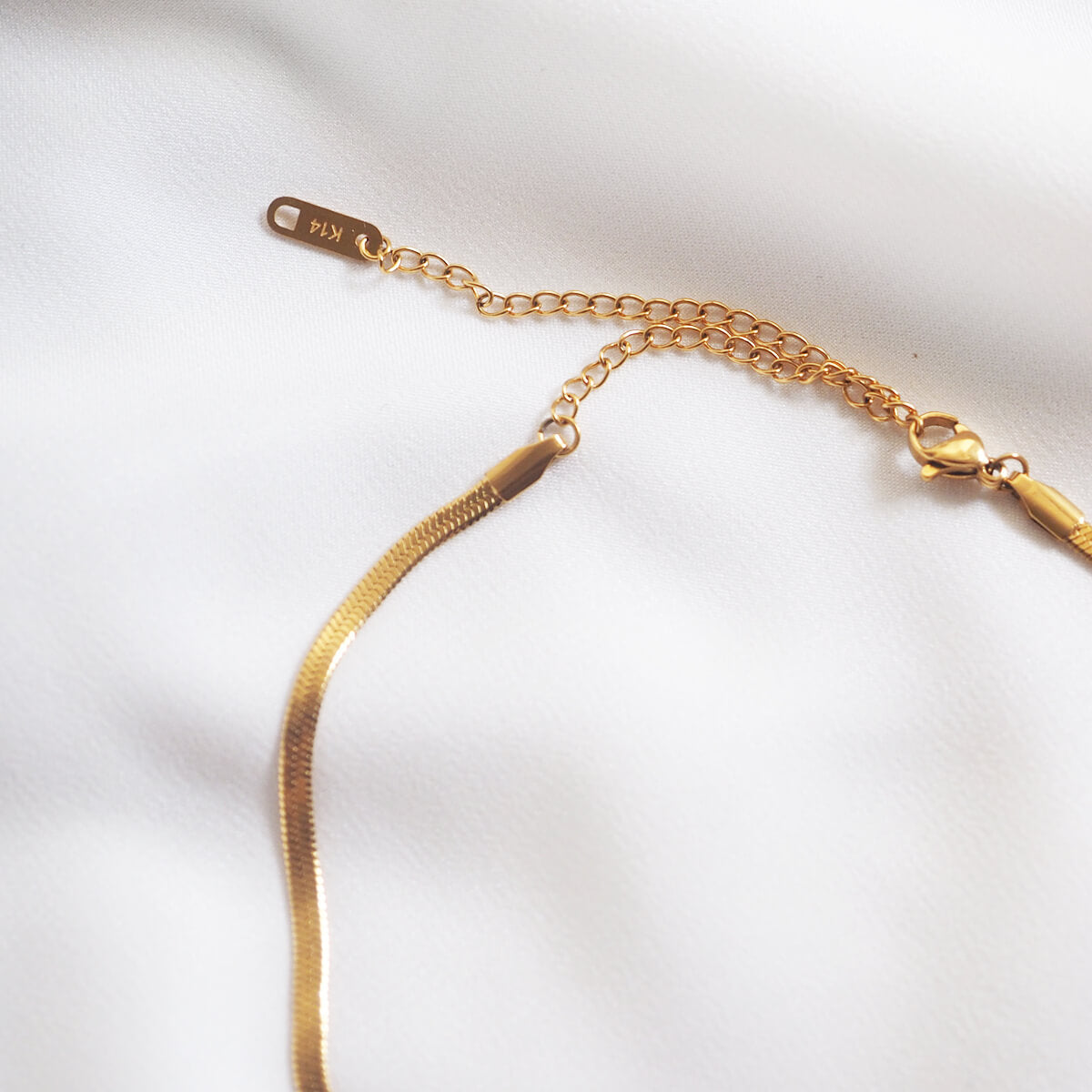 A stylish gold chain necklace adorned with a tiny gold coin, showcasing a blend of simplicity and sophistication.