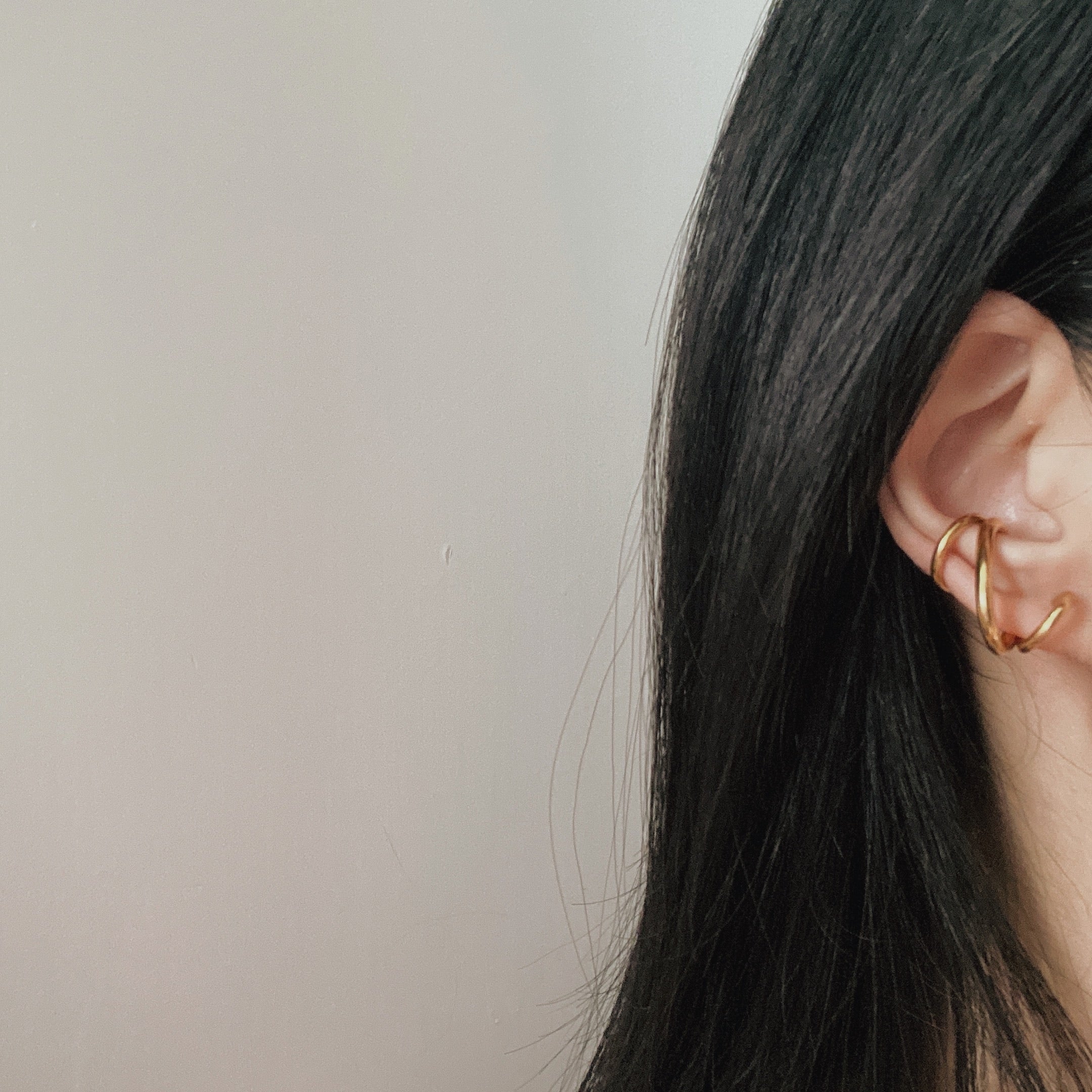 Elegant woman wearing a gold ear cuff, highlighting the sophisticated helix spiral design in 18K gold plating.