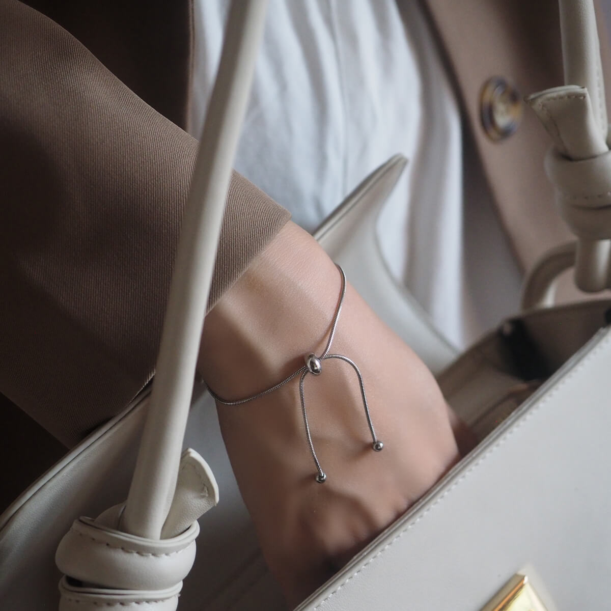 A woman's hand gracefully clutches a chic white purse, showcasing a blend of fashion and elegance.