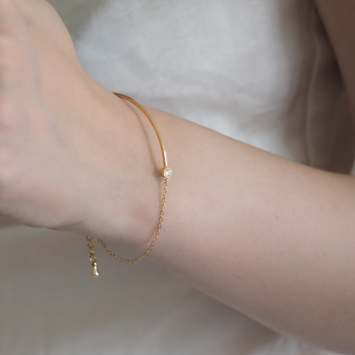 Close-up of the Vera Zirconia Bracelet with a diamond charm and elegant half-bangle style.