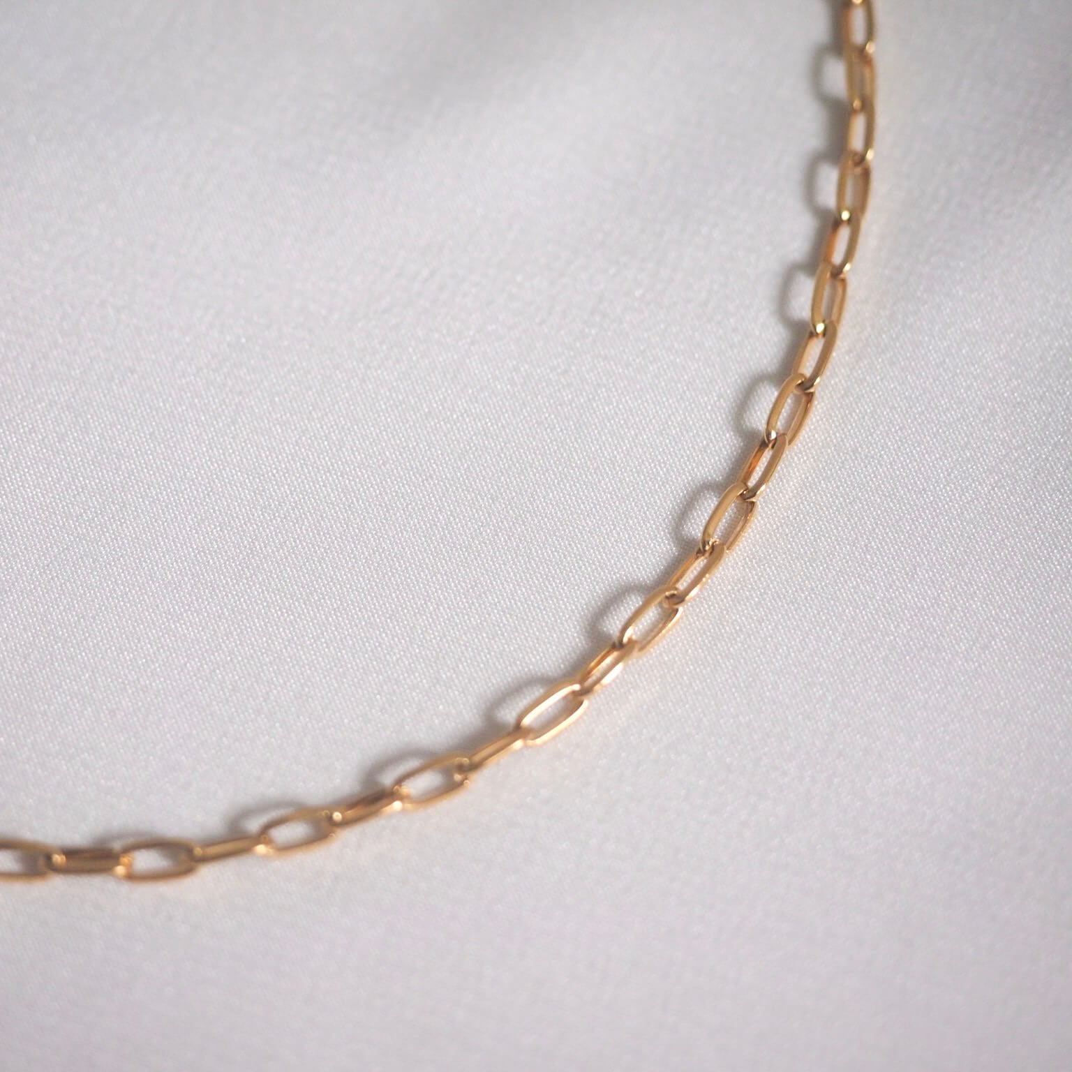 A shimmering gold chain necklace adorned with small links, showcasing a timeless and sophisticated design.