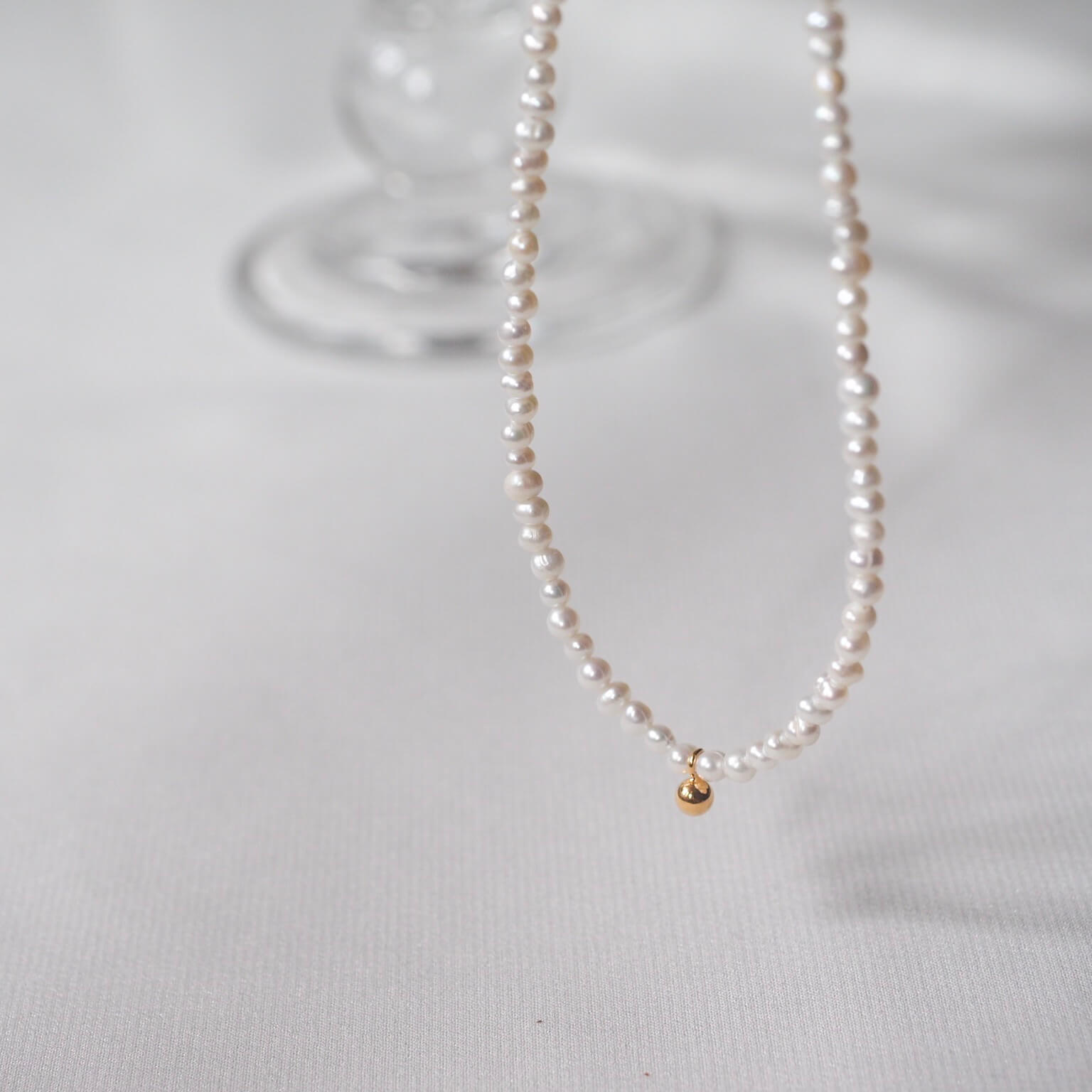 Elegant white pearl necklace featuring a tiny gold charm, ideal for a minimalistic and sweet style.