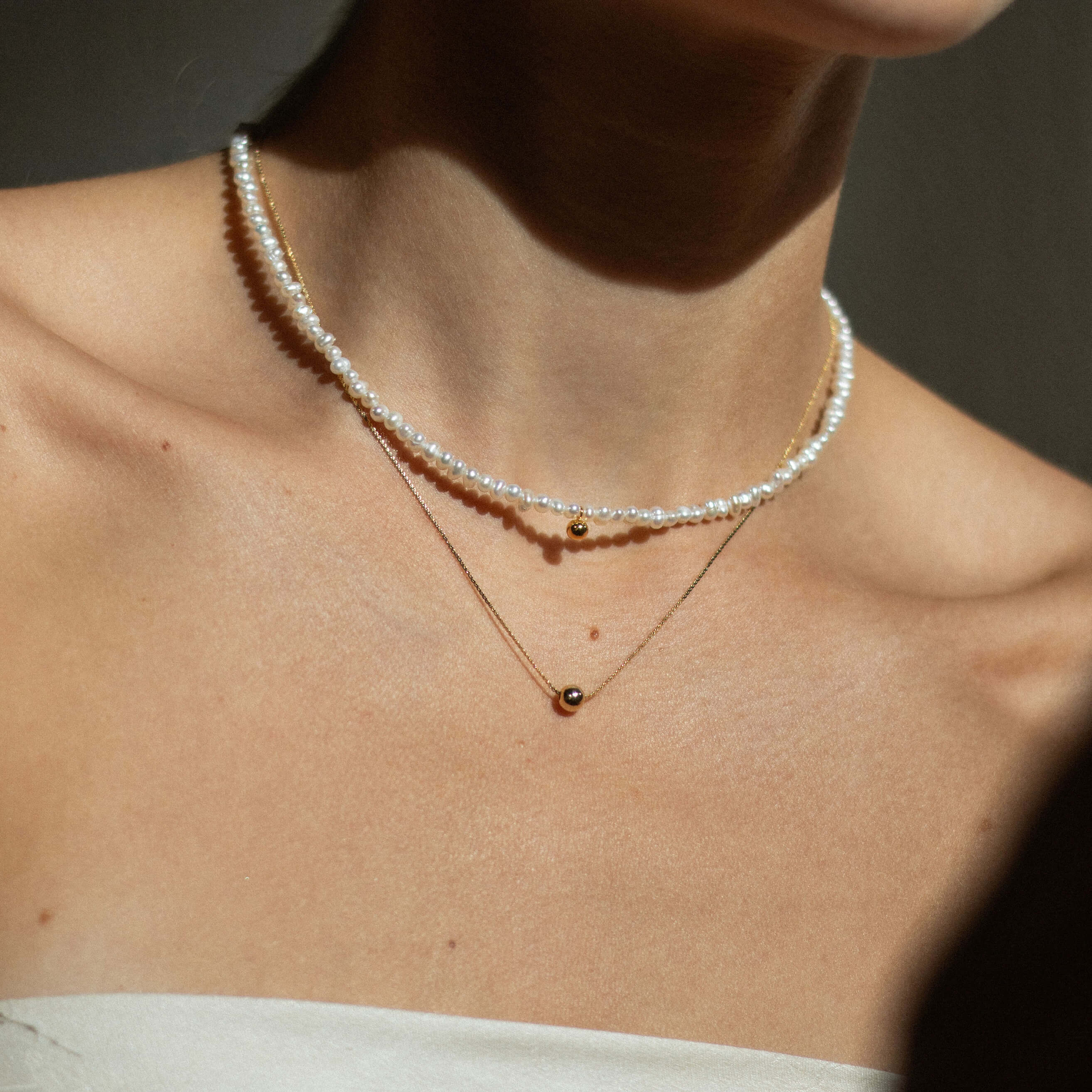 A woman showcases a delicate heart necklace, embodying elegance and minimalism with a touch of sweetness.
