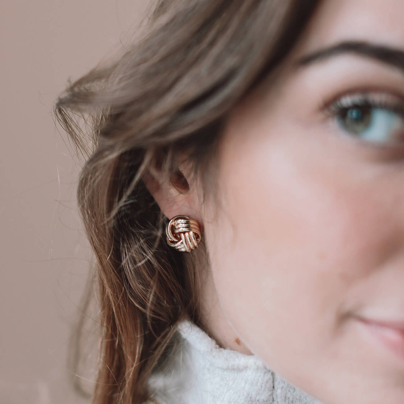 A woman showcases elegant gold earrings, highlighting their intricate design and stylish appeal.