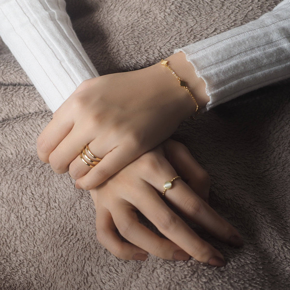 Hands of a woman displaying two beautiful rings with genuine opal stones, crafted from sterling silver and gold vermeil.