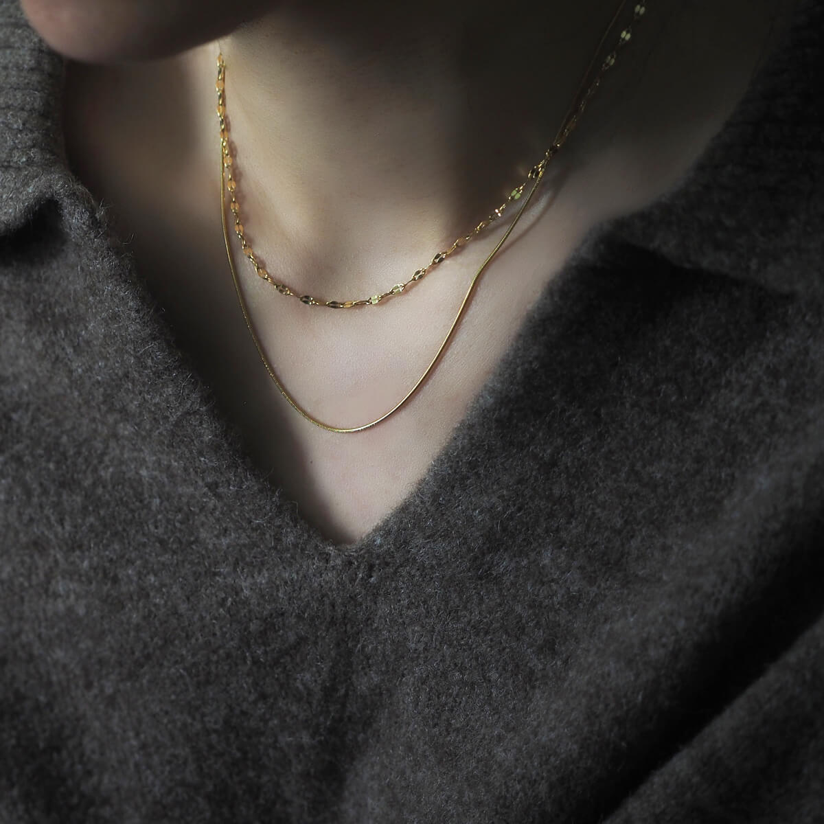 A stylish woman models a shimmering gold chain necklace, enhancing her look with a hint of luxury.