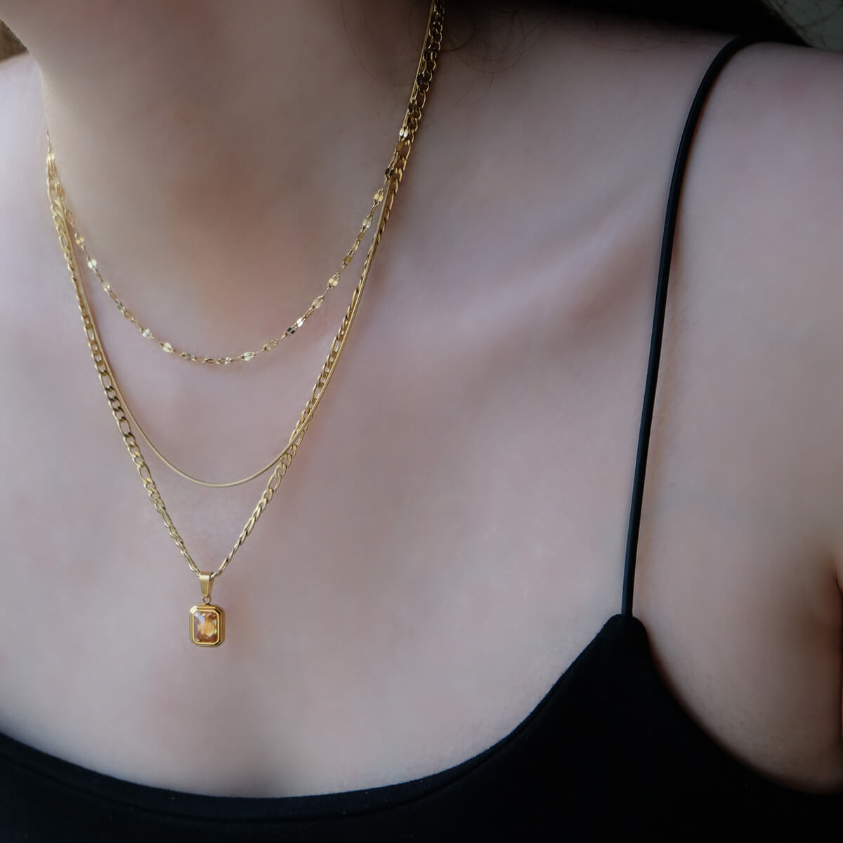 A woman elegantly adorned with a gold chain necklace, showcasing a touch of sophistication and style.