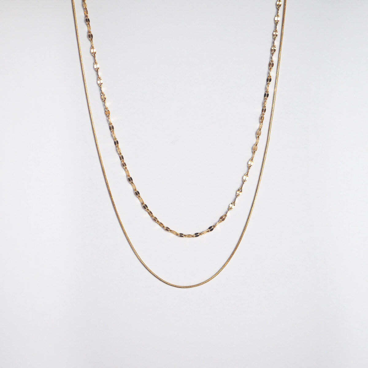 A stylish gold chain necklace with two layers of beads, highlighting a chic and contemporary aesthetic.