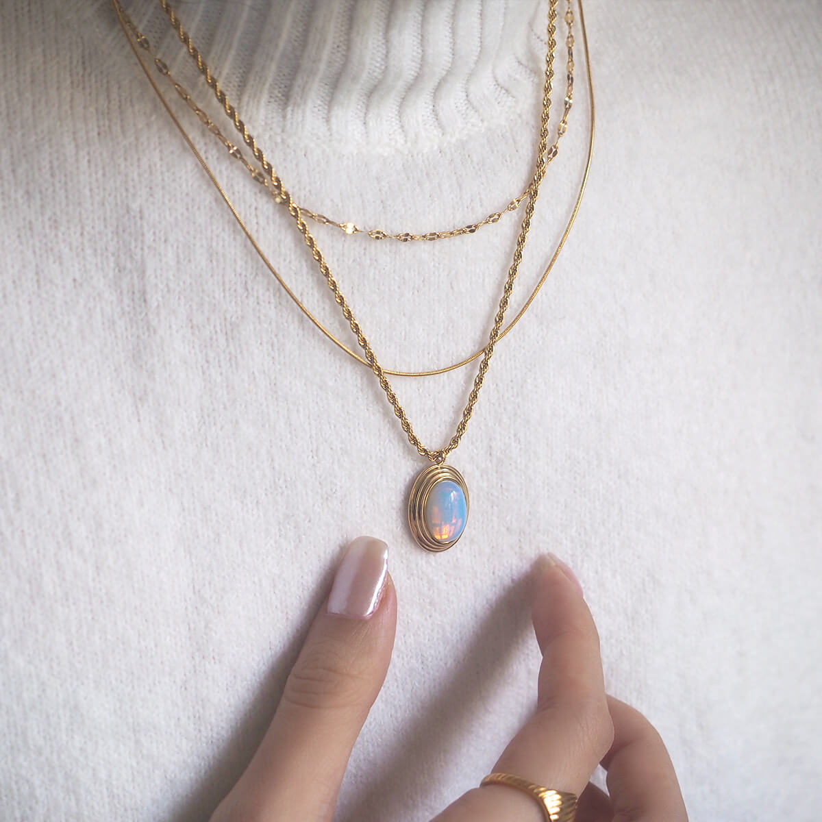 A woman elegantly wears a gold necklace featuring a striking blue stone, enhancing her style with a touch of color.