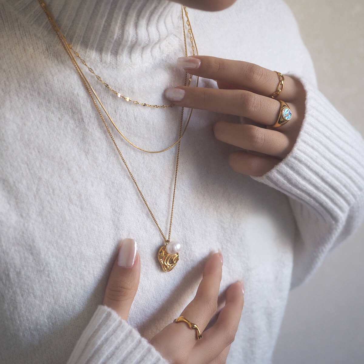 Stylish woman in a white sweater, complemented by shimmering gold jewelry, exuding elegance and comfort.