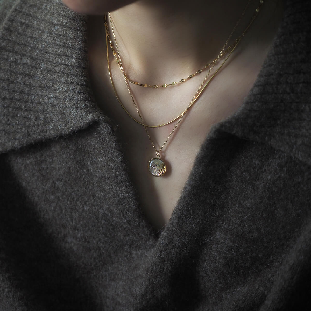 A woman showcasing a beautiful gold chain necklace, adding elegance to her outfit with a warm smile.